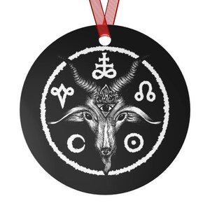 May include: Black and white round ornament with a white circle containing a goat head with horns, an eye, and flames. The circle is surrounded by symbols including a cross, a circle, a crescent moon, and a symbol that looks like a lion.