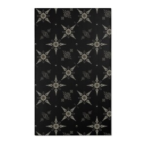 May include: Black and white patterned rug with a repeating design of stylized stars with a circular center. The rug has a subtle texture.