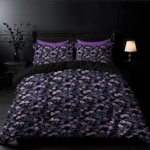 May include: A black duvet cover with a floral pattern in shades of purple and white. The duvet cover is on a bed with two purple pillowcases.