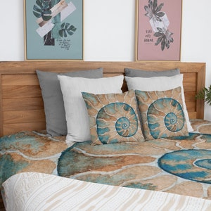 May include: A bed with a brown wooden headboard and a blue and brown patterned duvet cover. The duvet cover features a large spiral shell design. There are three pillows on the bed, two white and one gray.