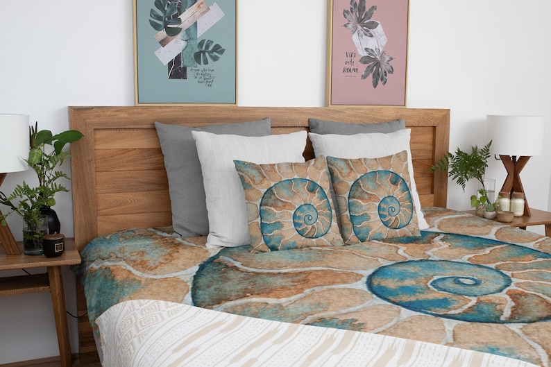 May include: A bed with a brown wooden headboard and a blue and brown patterned duvet cover. The duvet cover features a large spiral shell design. There are three pillows on the bed, two white and one gray.