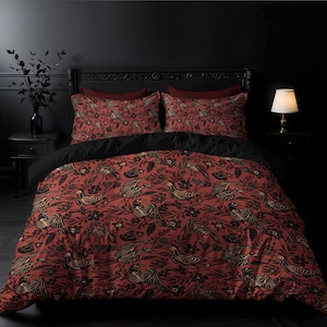 Pode incluir: Uma capa de edredom vermelha com um padrão de pássaros esqueléticos preto e branco e flores. A capa de edredom está em uma cama com fronhas pretas e vermelhas.