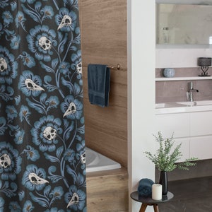 Puede incluir: Una cortina de ducha azul y blanca con un patr&oacute;n floral que presenta calaveras y p&aacute;jaros. La cortina est&aacute; colgada en un ba&ntilde;o con una ba&ntilde;era blanca y una pared de madera.