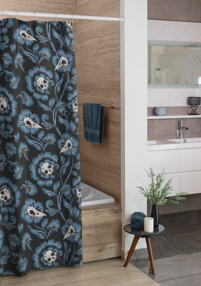 Puede incluir: Una cortina de ducha azul y blanca con un patr&oacute;n floral que presenta calaveras y p&aacute;jaros. La cortina est&aacute; colgada en un ba&ntilde;o con una ba&ntilde;era blanca y una pared de madera.