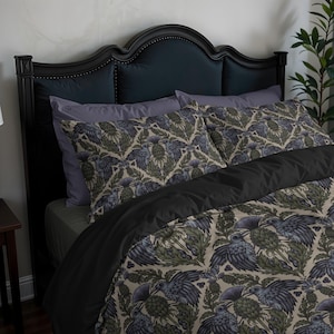 May include: A bed with a black headboard and bedding. The bedding includes a black duvet cover and pillowcases with a repeating pattern of blue and green birds and foliage on a beige background. The pillows are on top of a grey sheet.