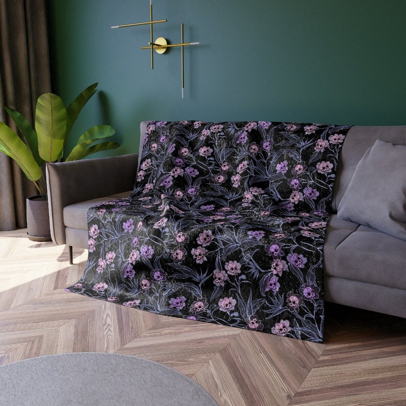 Throw blanket made of crushed velvet on grey crouch pushed against green painted walls.