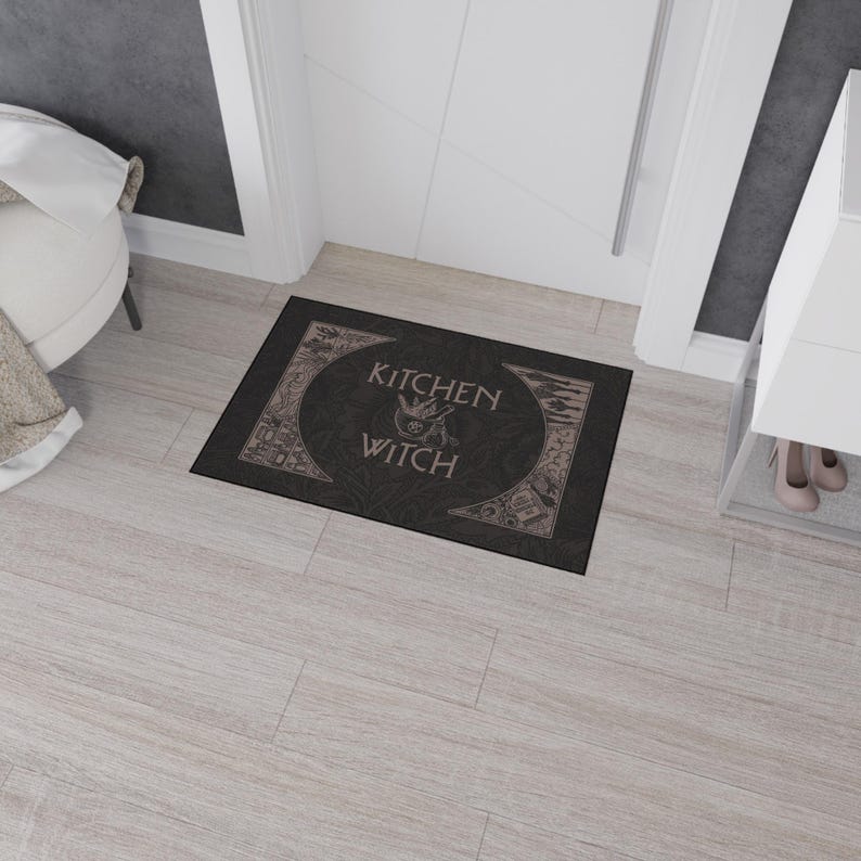 May include: Black doormat with the text "Kitchen Witch" in a decorative font. The text is surrounded by a circle with a cauldron and other witchy symbols.