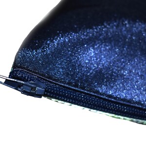May include: Close-up of a dark blue zipper on a fabric pouch. The zipper is metal and has a silver finish.