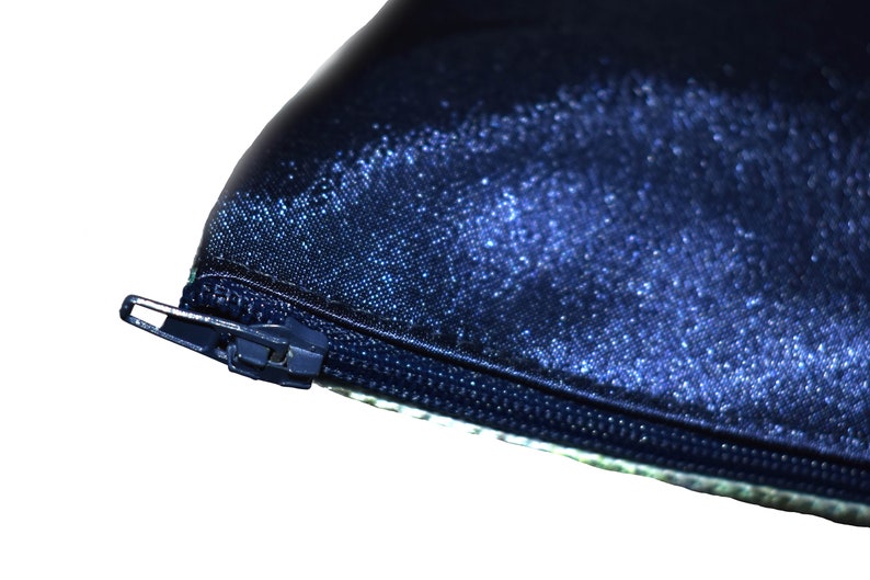 May include: Close-up of a dark blue zipper on a fabric pouch. The zipper is metal and has a silver finish.
