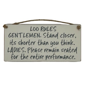 May include: A white wooden sign with black text that reads "LOO RULES GENTLEMEN. Stand closer, it's shorter than you think. LADIES. Please remain seated for the entire performance."