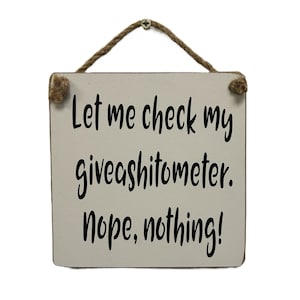 Könnte beinhalten: Ein weißes Holzschild mit einem braunen Bindfadenaufhänger. Das Schild trägt die Aufschrift "Let me check my giveashitometer. Nope, nothing!"