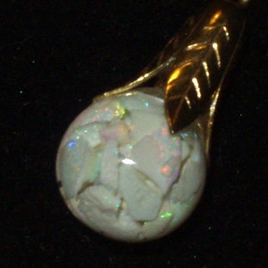May include: A gold pendant with a white opal gemstone. The opal has a unique, iridescent pattern.