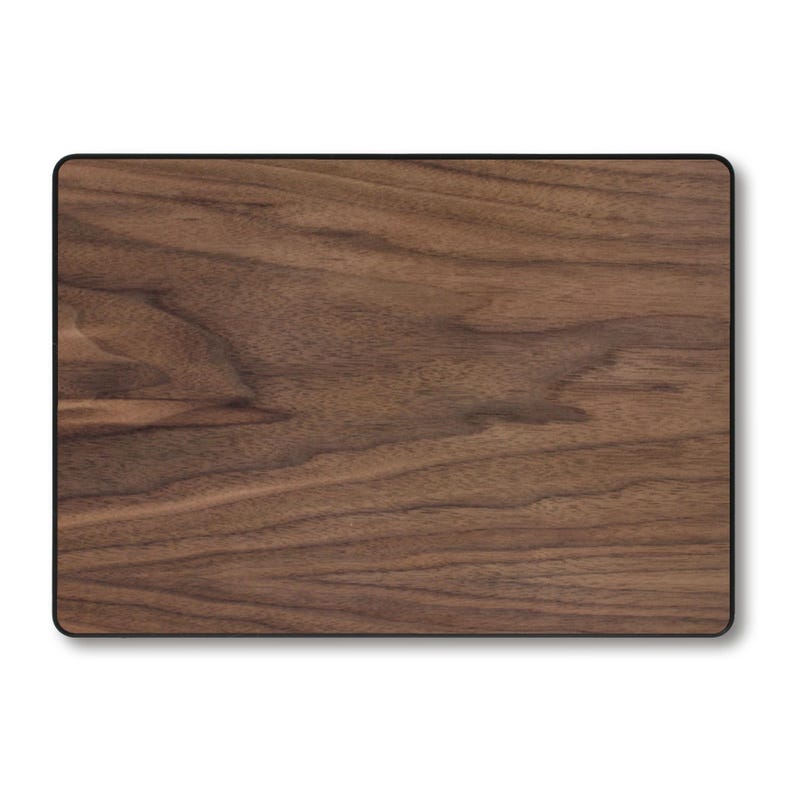 Puede incluir: Una tabla de cortar rectangular de madera con un patr&oacute;n de vetas de madera marr&oacute;n oscuro. La tabla tiene un borde negro y esquinas redondeadas. La veta de la madera tiene un aspecto natural y org&aacute;nico.