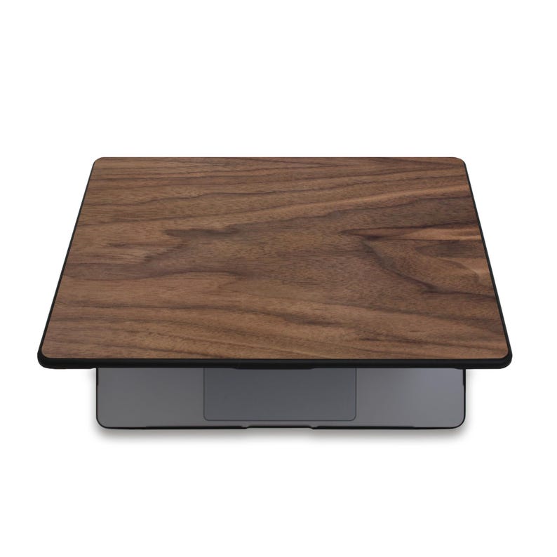 Puede incluir: Un ordenador port&aacute;til con una cubierta de madera. La cubierta tiene un patr&oacute;n de vetas de madera marr&oacute;n oscuro con un borde negro. El port&aacute;til es gris y tiene un dise&ntilde;o elegante y moderno. El patr&oacute;n de vetas de madera a&ntilde;ade un toque natural y elegante.