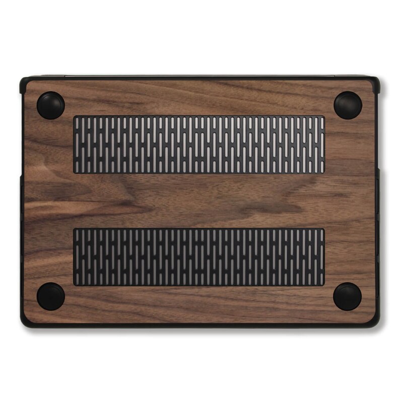Puede incluir: Una funda de madera para port&aacute;til con un acabado de veta de madera marr&oacute;n oscuro. La funda tiene un marco negro y cuatro patas de goma negras. Se ven dos rejillas rectangulares con un dise&ntilde;o de malla plateada.