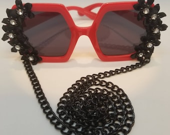 Röda iögonfallande solglasögon: Svarta bandblommor och kedja