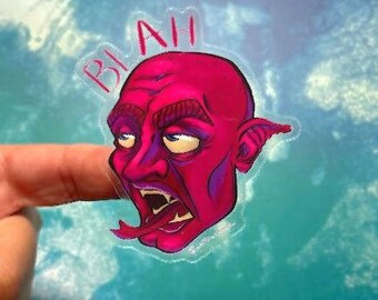 Può includere: Un adesivo di cartone animato rosa con una creatura dalla pelle rossa, una bocca grande e una lunga lingua. La creatura ha una grande fronte e un orecchio appuntito. L'adesivo ha la parola "Blah" scritta sopra la creatura.