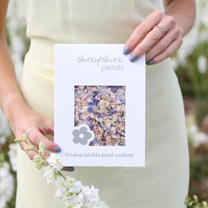 May include: A white card with the text "shropshire petals" and "biodegradable petal confetti". The card has a window showing pink, white, and blue flower petals.