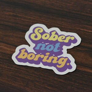 Magnet with "Sober not boring." printed on it. It is printed in pastel tones of purple, yellow blue and orange!