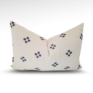 May include: A white pillow with a navy blue geometric pattern. The pillow is made of a soft, woven fabric and has a subtle sheen.