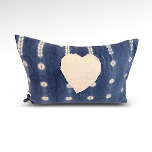 May include: A blue and white patterned pillow with a white heart-shaped patch in the center.