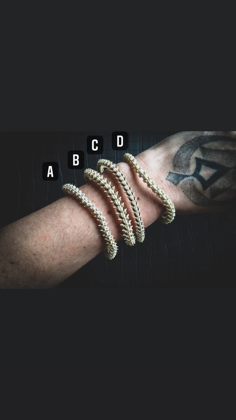 Peut inclure: Quatre bracelets en os blanc avec un motif en pointe. Les bracelets sont empil&eacute;s sur le poignet d'une personne, le plus petit bracelet en bas et le plus grand en haut.