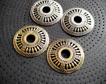 Peut inclure: Quatre cercles métalliques décoratifs avec des motifs complexes. Les cercles sont en deux finitions différentes : argent et or. Les cercles sont disposés en demi-cercle sur un fond noir.