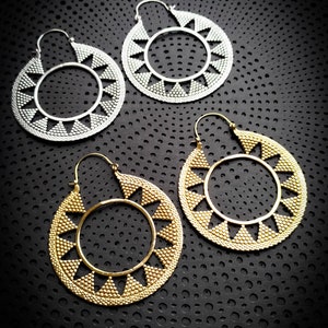 Peut inclure: Trois paires de grandes boucles d'oreilles créoles avec un motif géométrique. Les boucles d'oreilles sont en métal et ont une finition argentée et dorée.