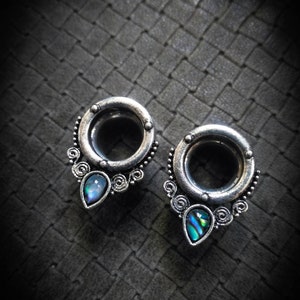 Peut inclure: Une paire d'écarteurs d'oreilles en argent avec un motif décoratif et des accents d'abalone nacré.