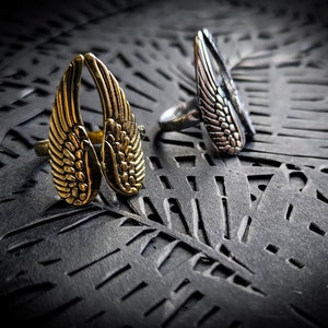 Peut inclure: Deux bagues en argent avec des motifs d'ailes d'ange. La bague de gauche est dorée et la bague de droite est argentée.