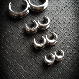 Peut inclure: Un ensemble de six boucles d'oreilles en argent de différentes tailles. Les boucles d'oreilles sont disposées par ordre de taille, les plus grandes en haut et les plus petites en bas.