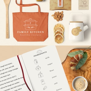 Puede incluir: Un cuaderno abierto en una p&aacute;gina con una lista de ingredientes para hacer croissants, incluyendo leche, az&uacute;car, harina, levadura, sal y mantequilla. El cuaderno est&aacute; sobre una superficie de madera con una taza de caf&eacute; y un croissant.