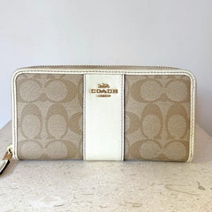 Carteira longa feminina Coach em lona com monograma e zíper, cor creme