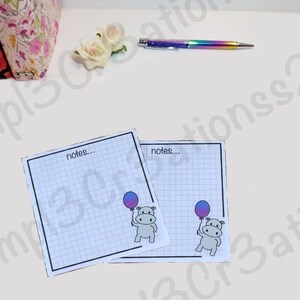 May include: Two gridded notepads with the word "notes..." printed at the top. Each notepad features a cartoon illustration of a grey hippopotamus holding a purple and blue balloon.