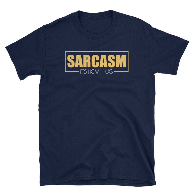 May include: A navy blue t-shirt with a gold rectangle that says "SARCASM - IT'S HOW I HUG"