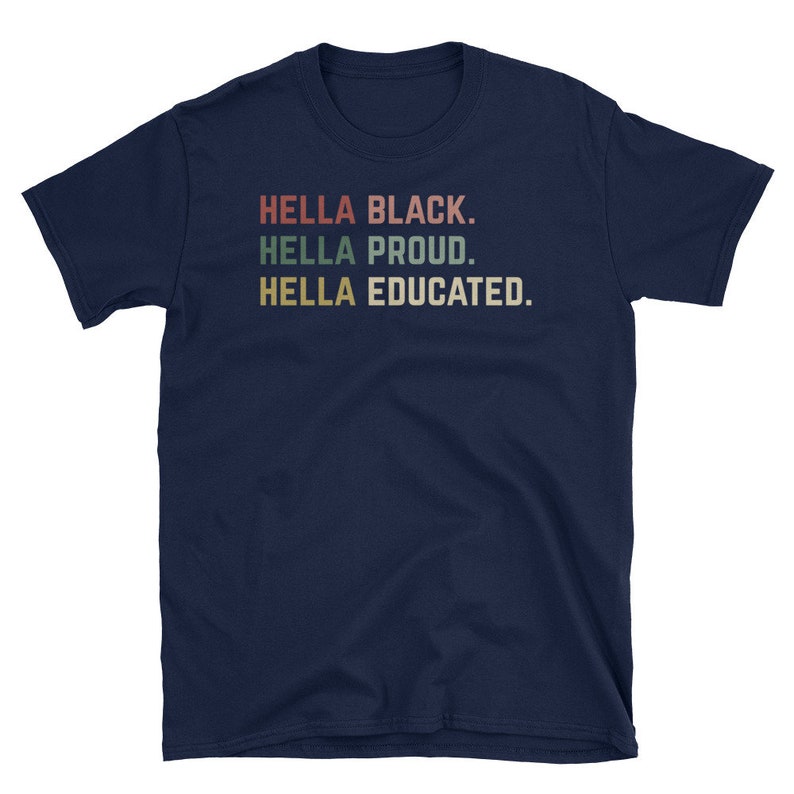 May include: A navy blue t-shirt with the phrases "HELLA BLACK. HELLA PROUD. HELLA EDUCATED." printed in a retro font. The text is in red, green, and tan colors. The shirt is a short-sleeved crew neck.