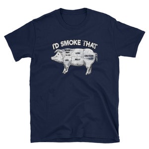 Puede incluir: Una camiseta azul marino con un gr&aacute;fico blanco de un cerdo con diferentes cortes de carne etiquetados. El texto "I'D SMOKE THAT" est&aacute; por encima del cerdo.