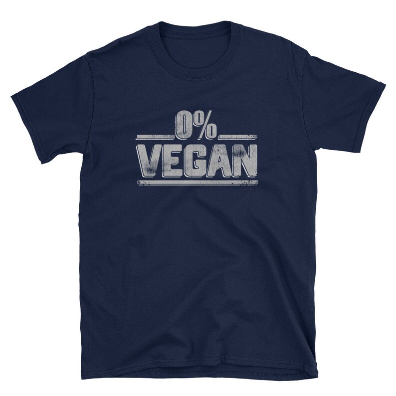 Pu&ograve; includere: Una t-shirt blu navy con una grafica bianca invecchiata che dice "0% VEGAN".