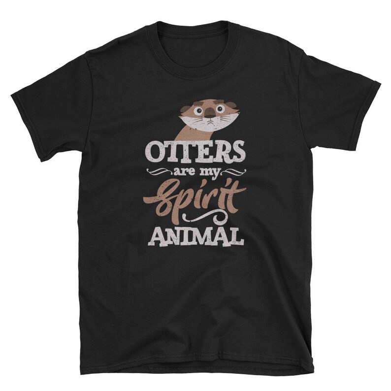 May include: Black t-shirt featuring a cartoon otter illustration above the text "Otters are my spirit animal" in a whimsical font. The otter has a neutral expression. The shirt is made of a soft material.