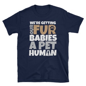 Puede incluir: Camiseta azul marino con texto blanco que dice "We're getting our fur babies a pet human". El texto est&aacute; en negrita, en una fuente de letra divertida. Una huella de pata est&aacute; incluida en el texto.