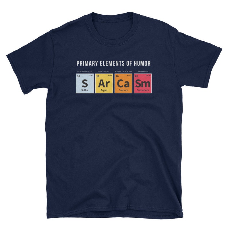 May include: A navy blue t-shirt with a white graphic of the periodic table elements, spelling out "S Ar Ca Sm" for "Sarcasm". The text "PRIMARY ELEMENTS OF HUMOR" is above the graphic.