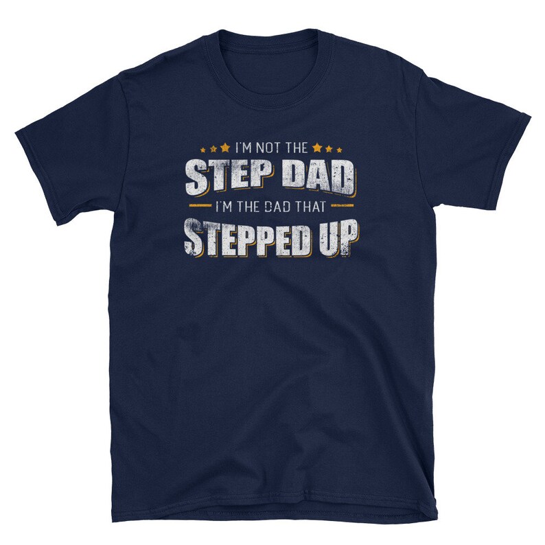 Op de afbeelding: Donkerblauw T-shirt met een witte, verweerde afbeelding met de tekst "Ik ben niet de stiefvader, ik ben de vader die een stap vooruit heeft gezet".