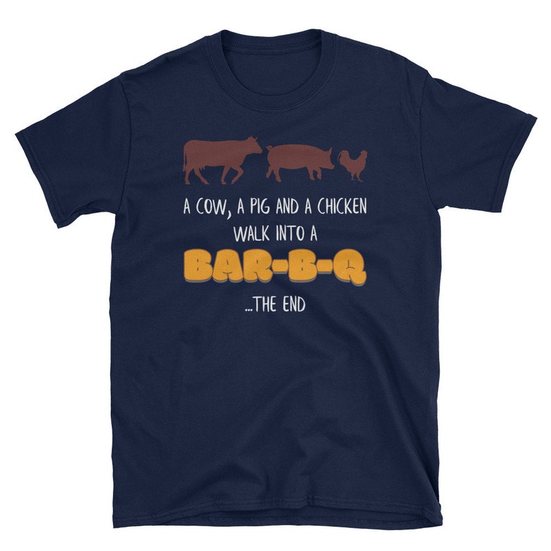 May include: A navy blue t-shirt with a white graphic of a cow, pig, and chicken walking into a bar-b-q. The text "A cow, a pig and a chicken walk into a BAR-B-Q... THE END" is printed on the shirt.