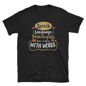 May include: Black t-shirt with a white graphic design that says "Speech Language Pathologists Have A Way With Words".