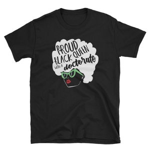 May include: Black t-shirt with a white graphic of a woman with an afro and sunglasses. The text "Proud Black Queen with a doctorate" is written on the graphic.