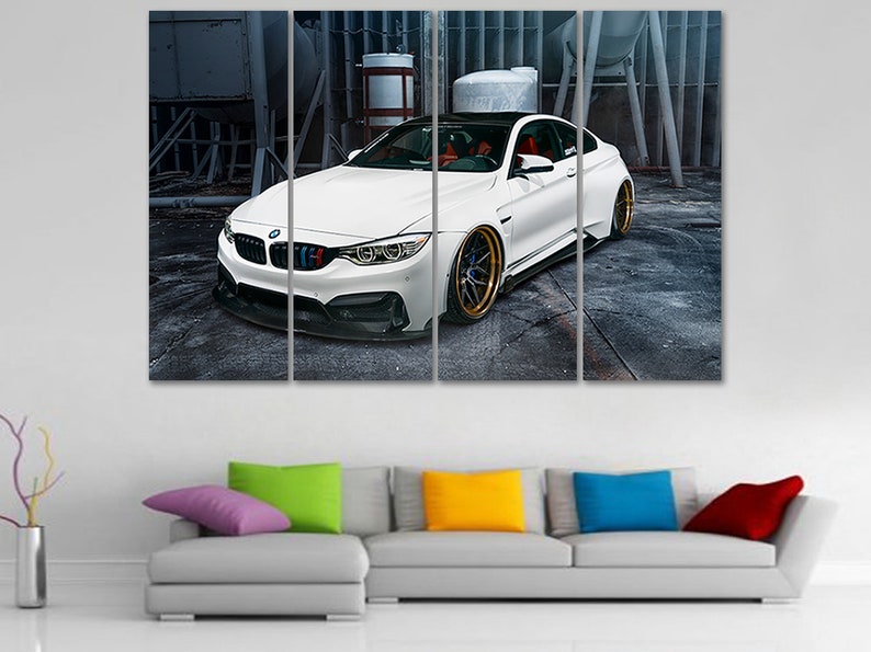 K&ouml;nnte beinhalten: Ein wei&szlig;er BMW M4 Sportwagen mit schwarzen Akzenten und goldenen Felgen steht in einer industriellen Umgebung. Das Auto ist in vier Paneele aufgeteilt, wodurch ein mehrteiliges Kunstwerk entsteht.