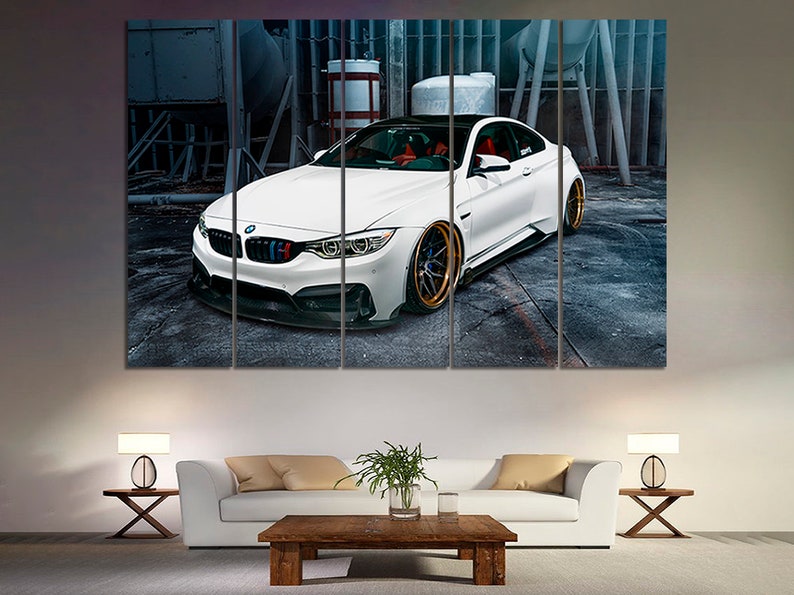 K&ouml;nnte beinhalten: Ein wei&szlig;er BMW M4 Sportwagen mit goldenen Felgen steht in einer Garage. Das Auto hat einen schwarzen Frontsto&szlig;f&auml;nger und einen schwarzen Heckdiffusor. Das Auto ist umgeben von grauen Betonw&auml;nden und einem Metallzaun.