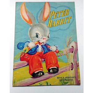 May include: A vintage children's book cover featuring a cartoon rabbit named Peter Rabbit sitting on a wooden fence. The rabbit is wearing red trousers, a blue and white striped shirt, and a bow tie. The book title is "Peter Rabbit" and the author is "Ruth E. Newton's Chubby Cubs".