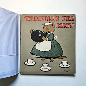 May include: A vintage children's book cover with a cartoon cat wearing a dress and holding a teapot. The title of the book is "Tabitha's Tea Party".
