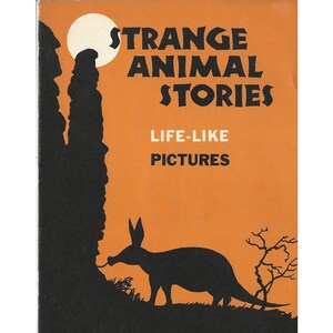 May include: An orange book cover with black text that reads "Strange Animal Stories" and "Life-Like Pictures". The cover also features a black silhouette of an aardvark and a moon.